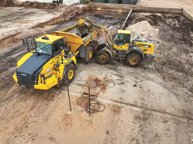 A Backyard Environmental Solutions operator uses a Komatsu WA380 wheel loader to place material into a Komatsu HM400 articulated truck.