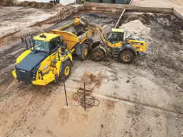 A Backyard Environmental Solutions operator uses a Komatsu WA380 wheel loader to place material into a Komatsu HM400 articulated truck.